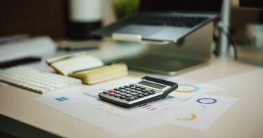 A calculator next to a laptop, for working out whether you can claim ChatGPT on tax in Australia